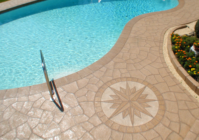 Pool deck with decorative concrete and stamped compass design.