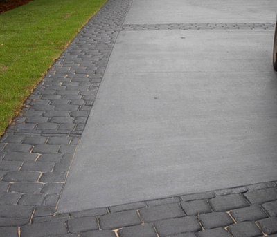 Gray broom finished concrete driveway with stamped brick concrete edging.